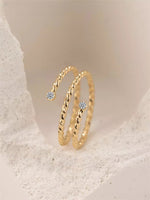 Gold filled twisted ring with moissanite accents on a light beige background