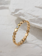 Gold filled ring with small round beads and a central moissanite on a white stone background