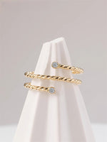 Gold filled twisted ring with moissanite accents on a white cloth cone