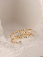 Gold filled twisted ring with moissanite accents on a white/gray stone background