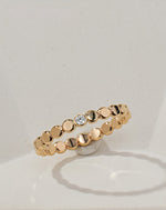 Gold filled ring with small round beads and a central moissanite on a light beige background