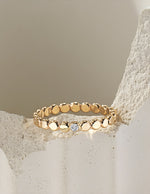 Gold filled ring with small round beads and a central moissanite on a light beige stone