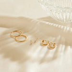 Gold hoop earrings on a beige fabric background