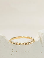 Gold filled ring with a textured design on a light beige background