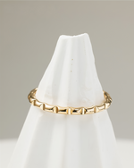 Gold filled ring on a white cone-shaped stand against a neutral background