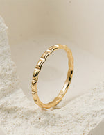 Gold filled ring with a textured design on a light stone background
