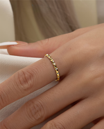 Gold filled ring on a finger with a neutral background