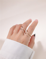 Hand wearing multiple gold filled rings on a light background