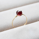 Gold filled ring with a red gemstone on a white cloth background