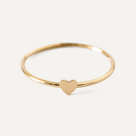 Gold filled ring with a heart charm on a light gray background