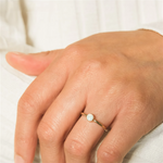 Gold filled ring with a central opal stone on a models hand