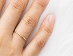 Gold filled ring on persons finger with white background
