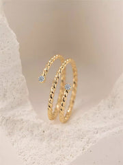 Gold filled twisted ring with moissanite accents on a light beige background
