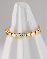 Gold filled ring with small round beads and a central moissanite on a white cone shaped cloth
