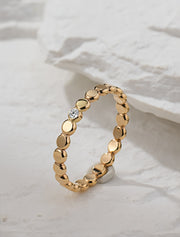 Gold filled ring with small round beads and a central moissanite on a white stone background