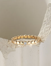 Gold filled ring with small round beads and a central moissanite on a light beige stone