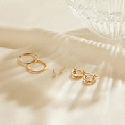 Gold hoop earrings on a beige fabric background