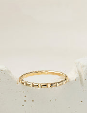 Gold filled ring with a textured design on a light beige background