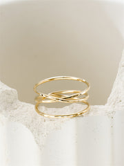 Gold filled ring with a criss-cross design on a textured beige surface