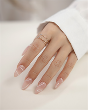 Hand with pink nail polish and gold filled ring on a light background
