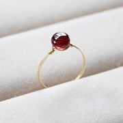 Gold filled ring with a red gemstone on a white cloth background