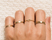 All sorts of gold filled rings on models hand. Textured rings, heart charm ring, rope tie ring etc.