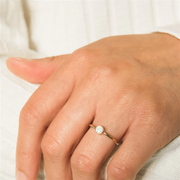 Gold filled ring with a central opal stone on a models hand
