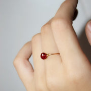 Hand with a gold filled ring with a red gemstone